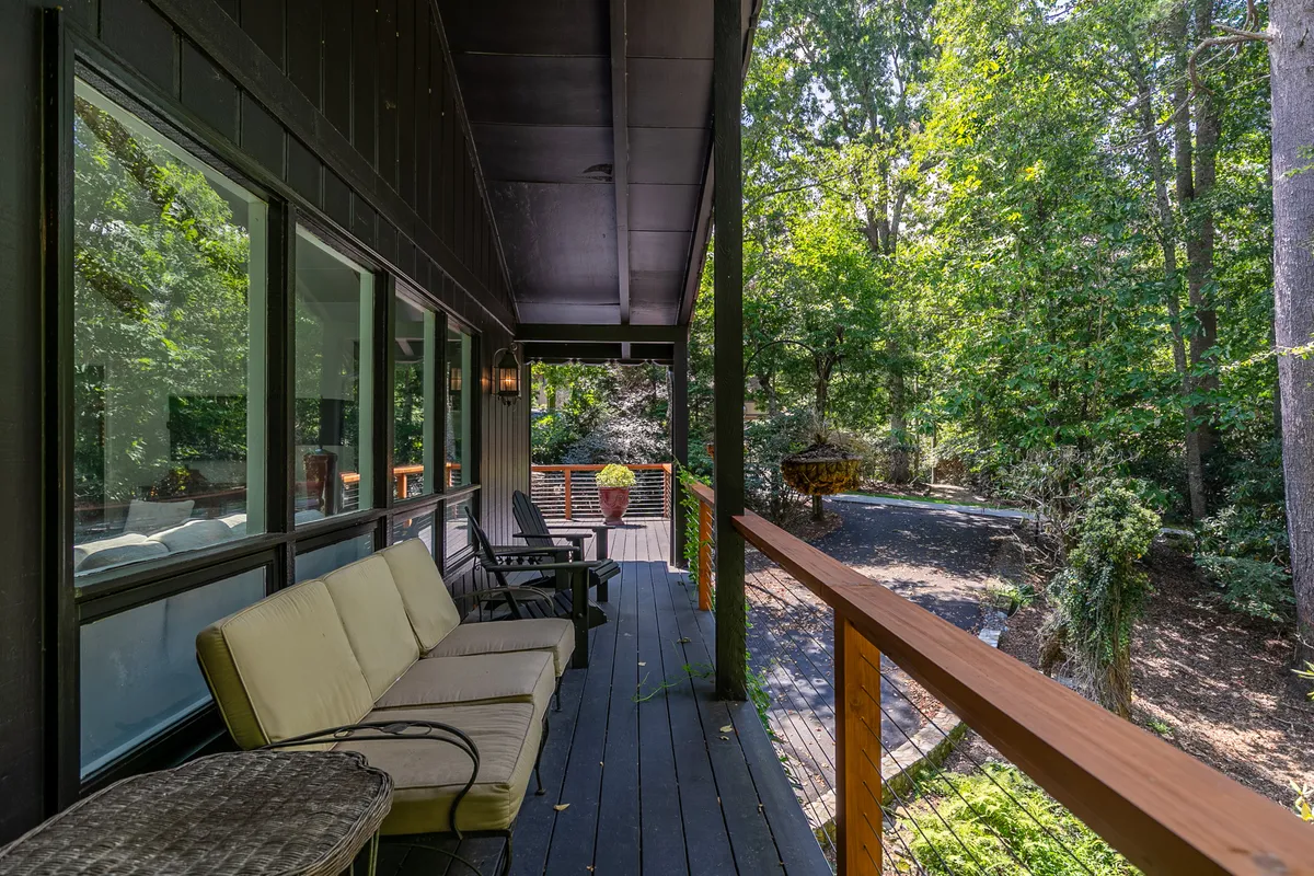 A cozy outdoor seating area framed by a wooden railing and surrounded by dense greenery. The seating is intimate and comfortable, ideal for enjoying the crisp mountain air or a quiet meal outdoors. The overall feel is tranquil, perfect for reading, sipping coffee, or sharing a quiet conversation.