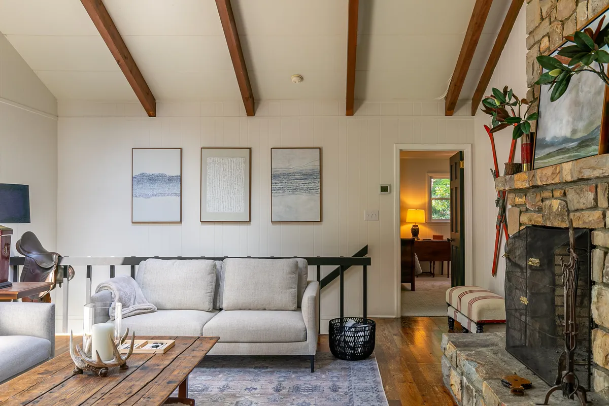 A cozy living area is arranged around a welcoming fireplace, with a comfortable sofa, coffee table, and curated artwork adorning the walls. The space radiates warmth and relaxation, suggesting evenings spent unwinding.
